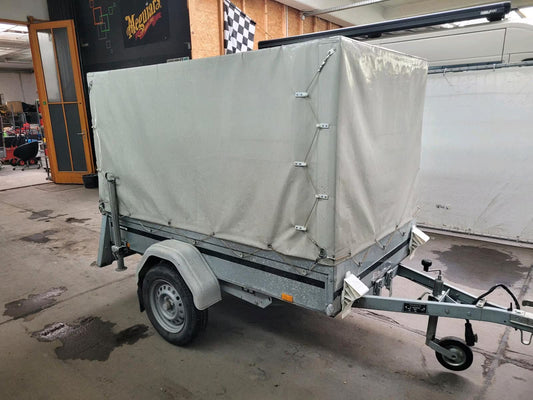 Ein weißer, Geschlossener Kippanhänger, hier von der Seite aufgenommen.