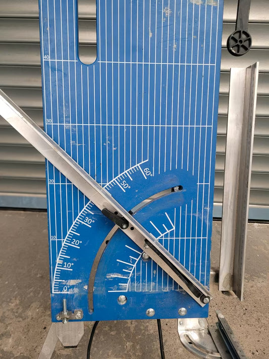 Ein blauer Glühdraht mit silbernen Maßanlagen. Er steht auf drei Beinen und hat eine Fläche zum schneiden, sowie silberne Maßanlagen zum Einstellen von Winkeln und Abmessen von Längen. Die vorhandenen Winkel haben eine Bandbreite von 0 bis 60 Grad.