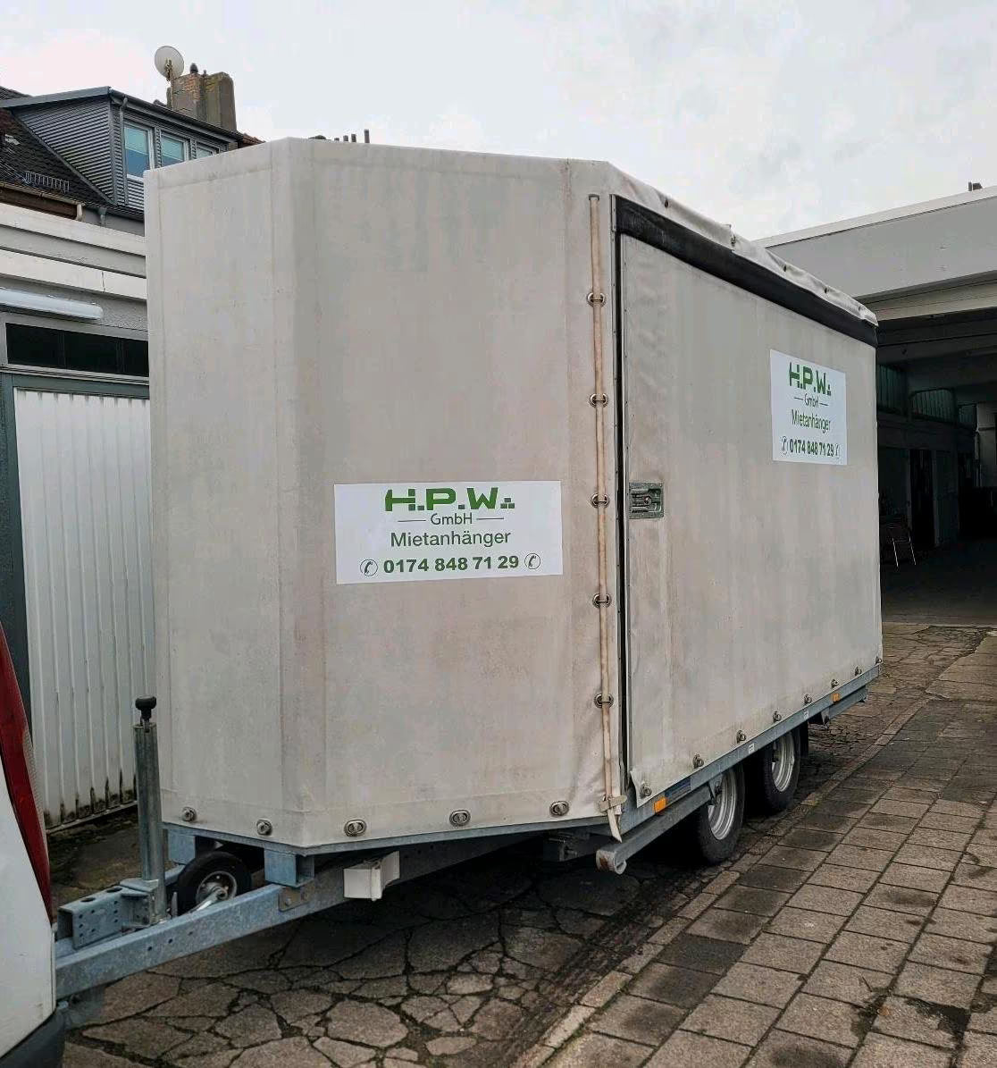 Ein großer, weißer Anhänger fürs Auto mit geschlossenen Seiten und Dach.