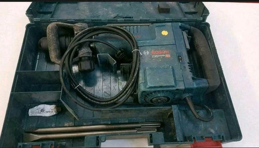 Türkis-schwarzer Stemmhammer in der Box mit Kabel und zwei großen Meißelaufsätzen.