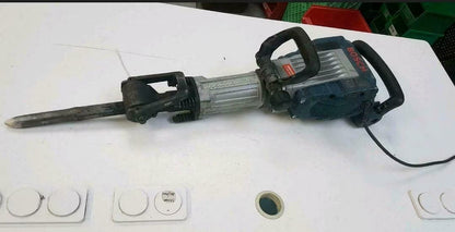 Türkis-schwarzer Stemmhammer mit Kabel und großem Meißelaufsatz. Mit einem seitlichen Handgriff.