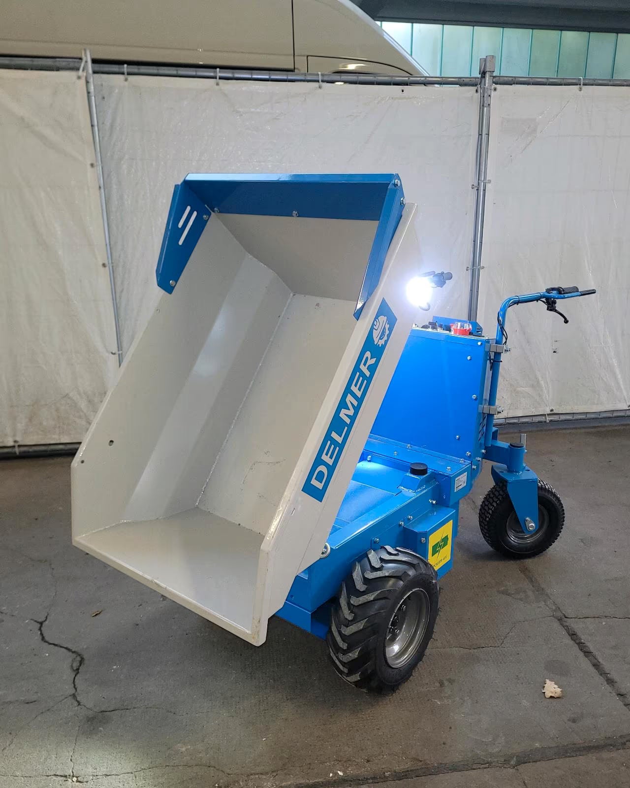 Blauer Akku Dumper oder auch Elektro Minidumper in Schüttposition.