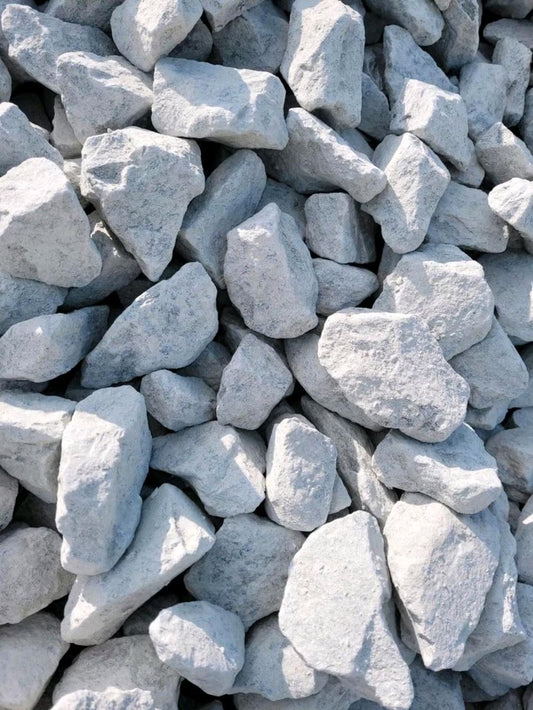 Weiß-gräulicher Bahnschotter von nahem betrachtet.