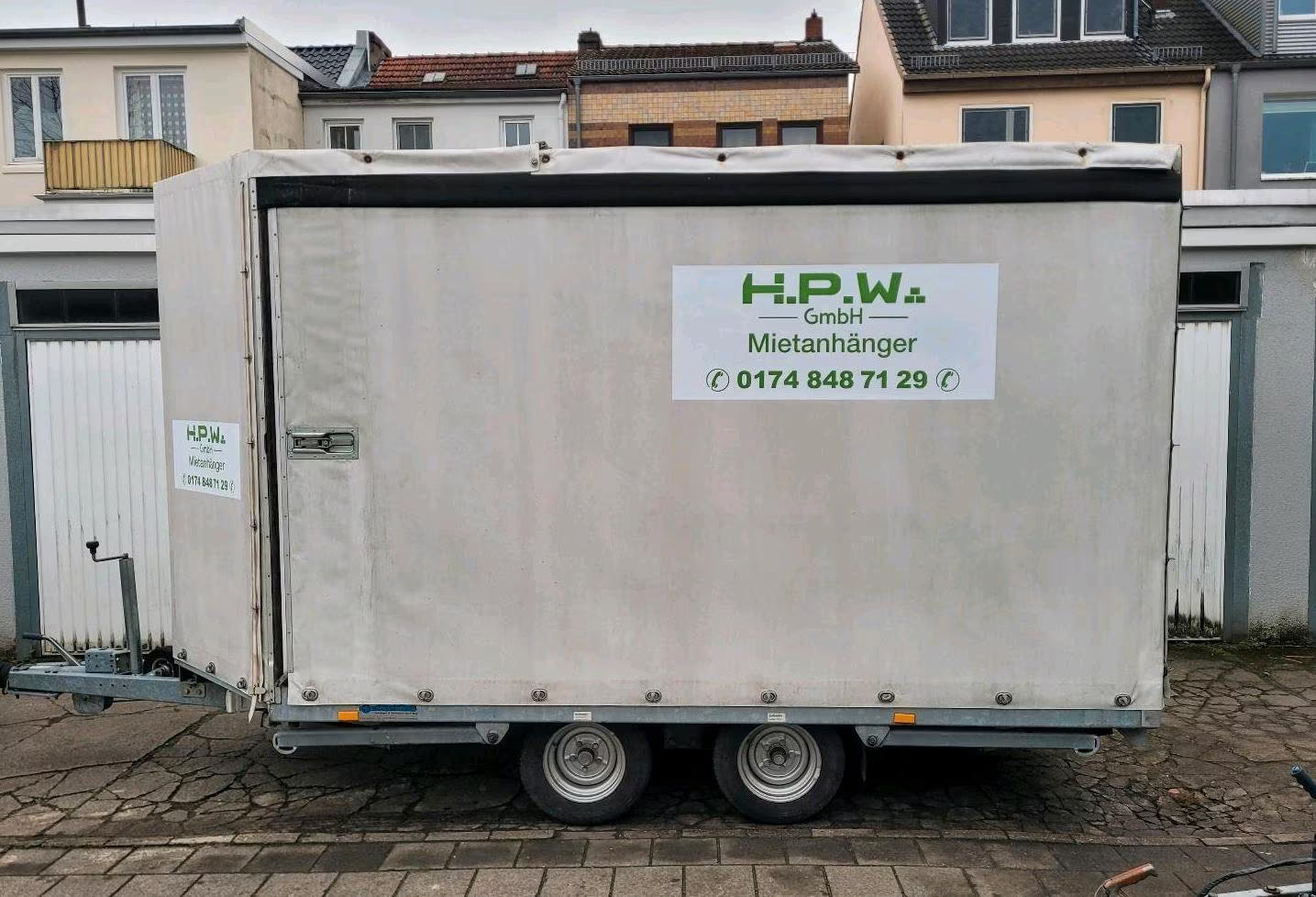 Ein großer, weißer Anhänger fürs Auto mit geschlossenen Seiten und Dach.