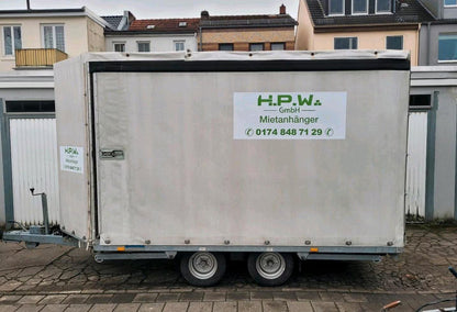 Ein großer, weißer Anhänger fürs Auto mit geschlossenen Seiten und Dach.