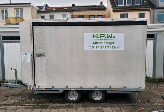 Ein großer, weißer Anhänger fürs Auto mit geschlossenen Seiten und Dach.