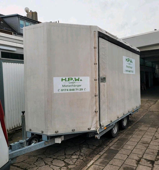 Ein großer, weißer Anhänger fürs Auto mit geschlossenen Seiten und Dach.