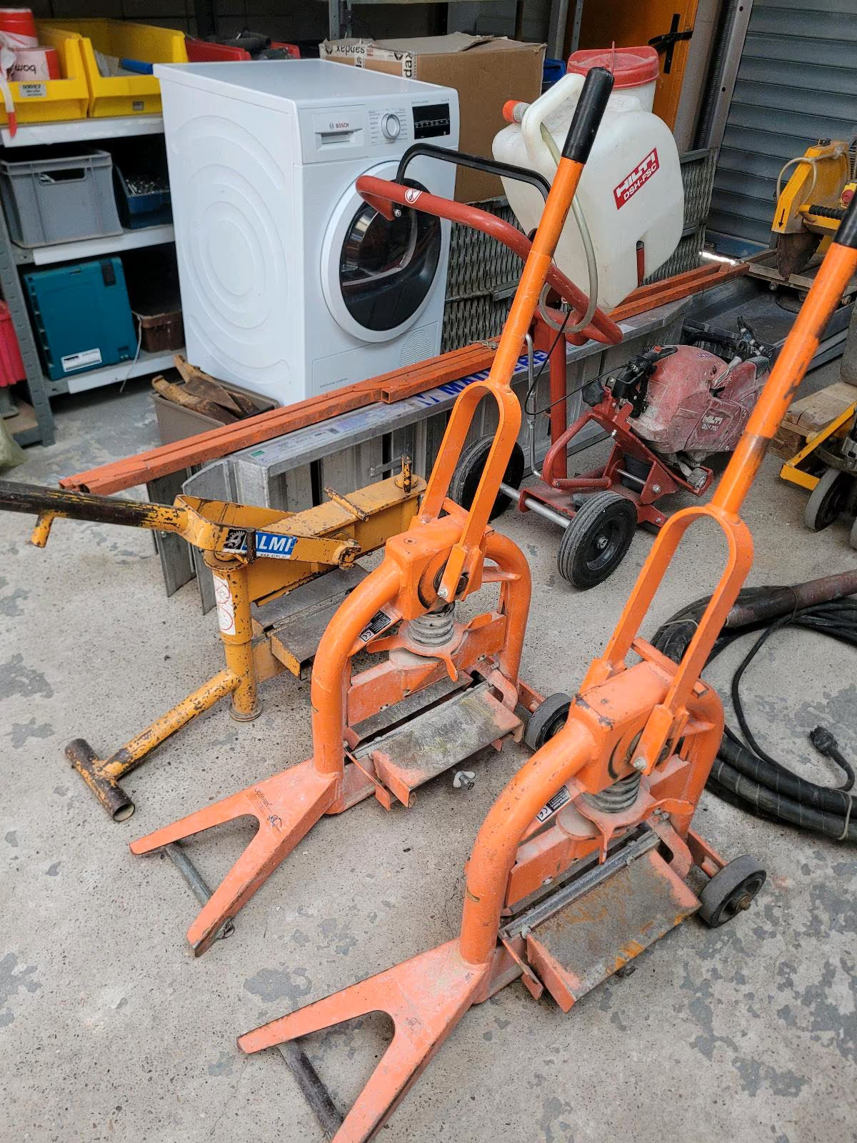 Orangener Steinspalter mit Rollen auf einer Seite und einem großen Hebel zum Spalten von Steinen.