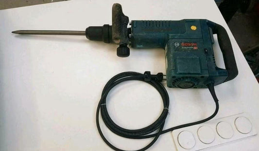Türkis-schwarzer Stemmhammer mit Kabel und großem Meißelaufsatz. Mit einem seitlichen Handgriff.