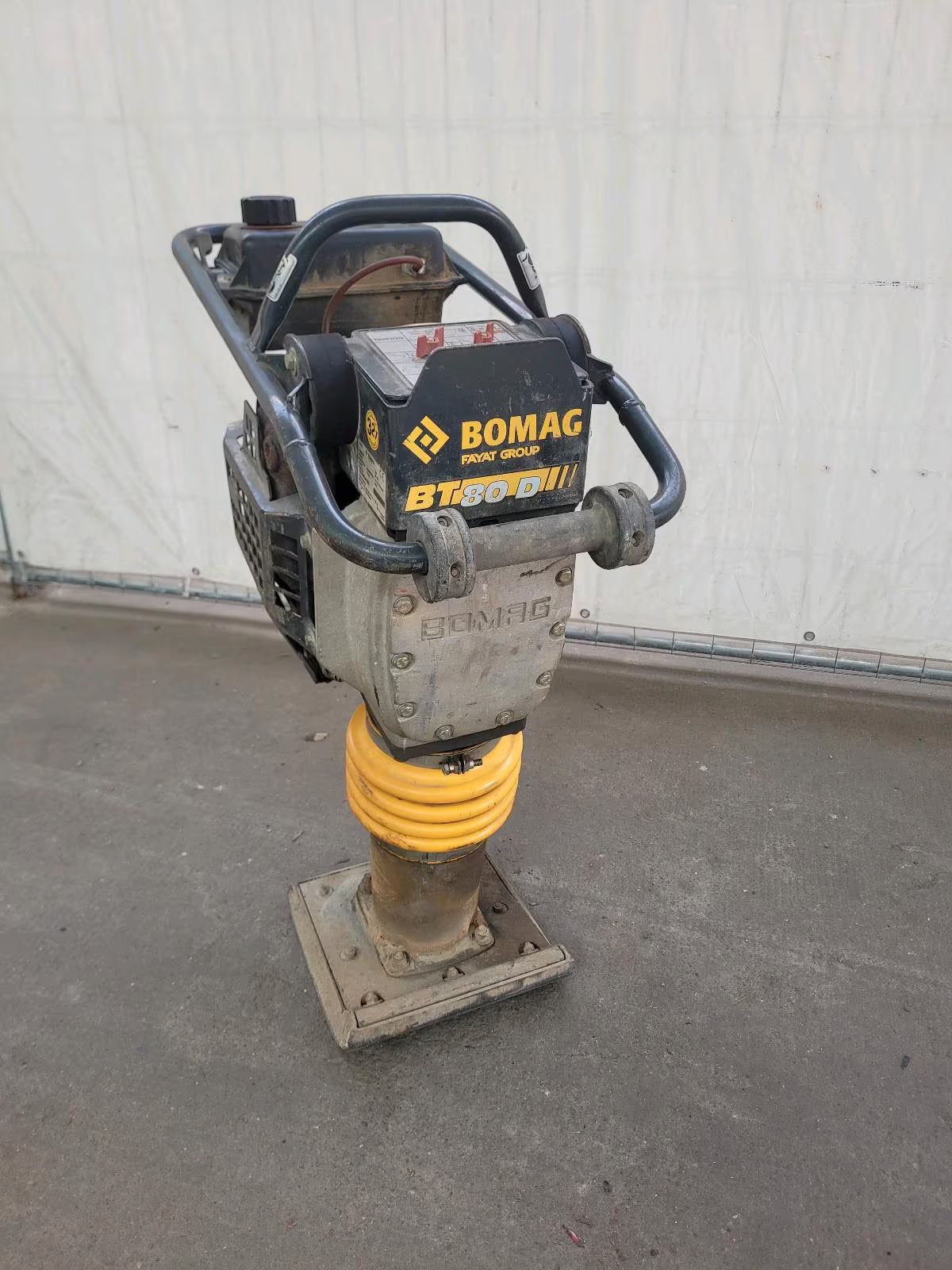 Ein schwarz-gelber Vibrationsstampfer mit großem Motor und einer Bodenplatte, die sich ideal zum Stampfen eignet.